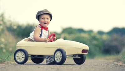 Kleiner Junge im Spielzeug VW Polo mit Autoversicherung